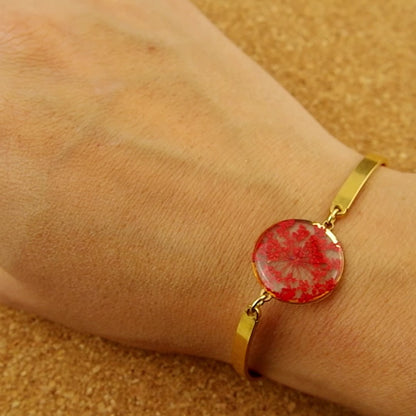 Magnus gold bangle bracelet with red QAL flower inclusion